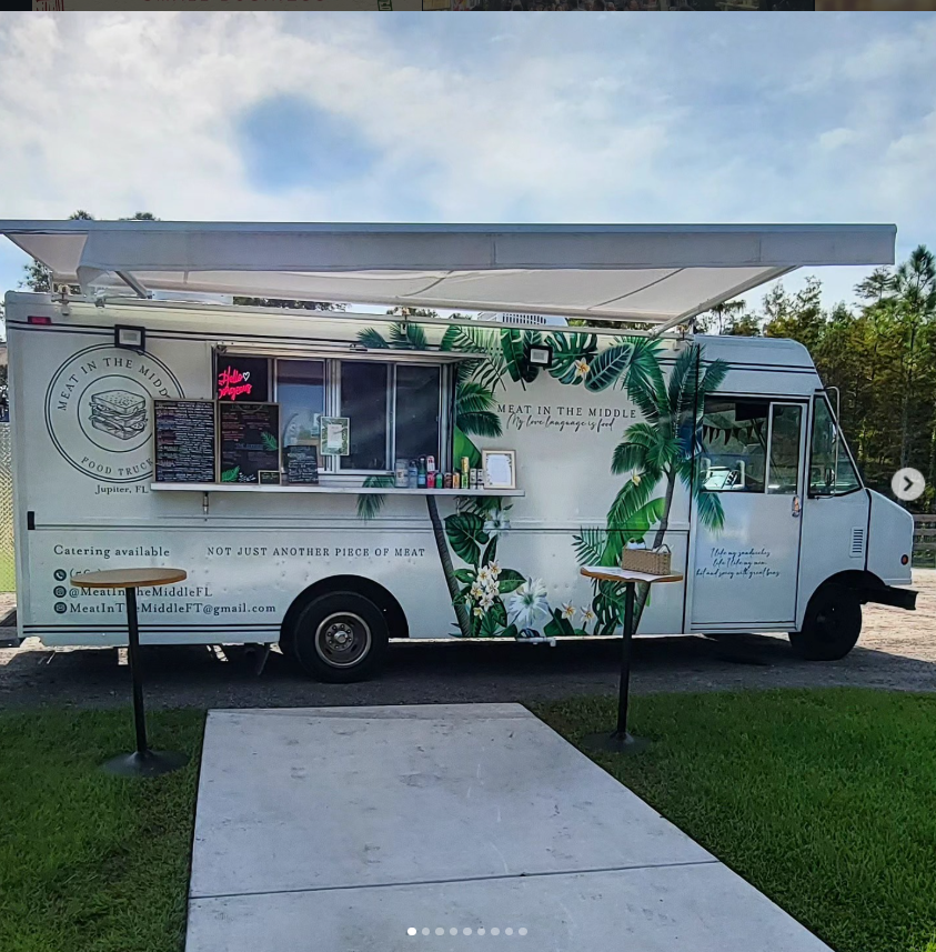 Meat in the Middle food truck parked with awning open, decorated with tropical palm illustrations
